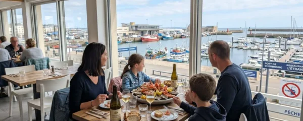 Une famille vue de dos attablée près d'une grande baie vitrée donnant sur le port de Cherbourg, plateau de fruits de mer au centre de la table