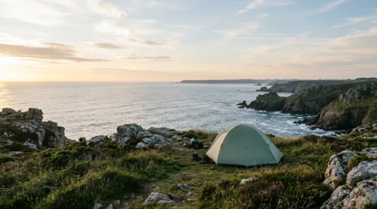 Campeur contemplant la côte bretonne sauvage au lever du soleil, tente en arrière-plan, ambiance paisible et authentique