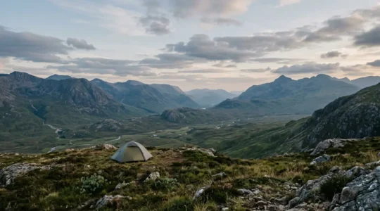 Vue panoramique d'un campement solitaire dans un paysage montagneux préservé avec une tente isolée
