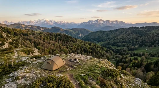 Vue aerienne d'un campement en tente installe dans un paysage naturel francais avec montagnes en arriere-plan