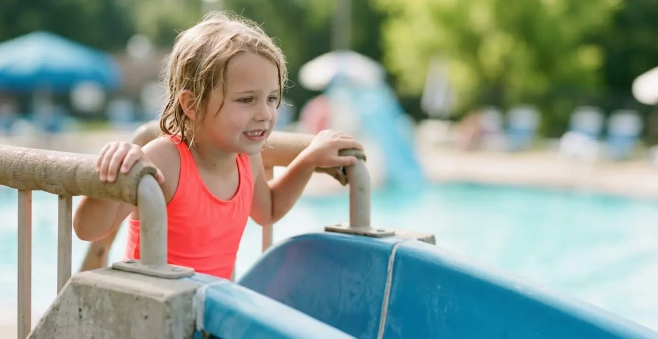 Enfant préparant sa descente sur un toboggan aquatique sous la surveillance d'un maître-nageur