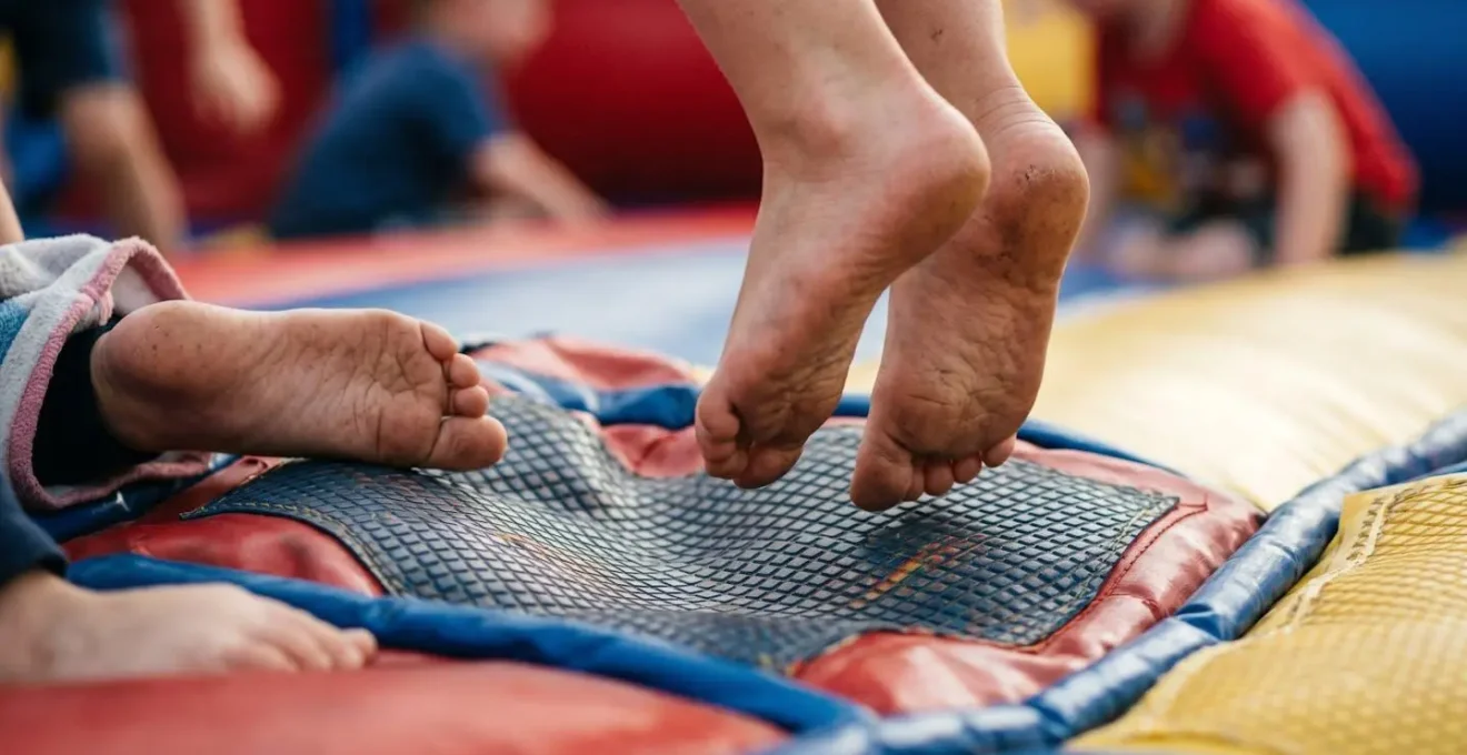 Gros plan sur les pieds nus d'enfants rebondissant sur une surface gonflable colorée